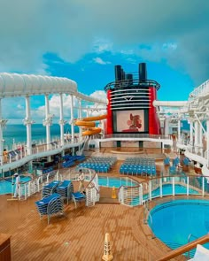 the deck of a cruise ship with blue chairs and a large screen on it's side