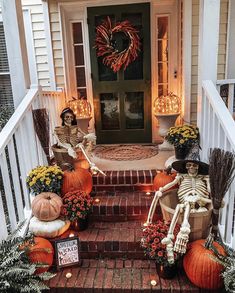 halloween decorations on the front steps of a house with skeletons and pumpkins in pots