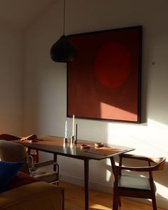 a living room with a table and chairs in front of a large painting on the wall