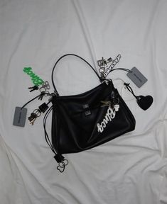 a black purse sitting on top of a white bed next to a key chain and cell phone