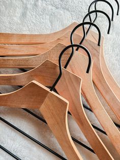 four wooden hangers are lined up on a white blanket with black iron bars in the middle