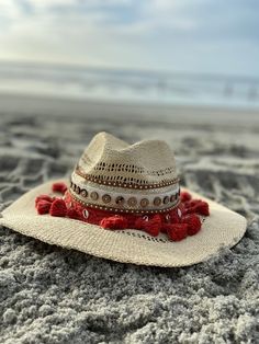 Decorated straw hat, fits size medium to small. Our Dahlia hat is a beautiful and comfortable must have for any occasion. It's decorated with red pom pom, gold and silver seashells, brown button trim and camel suede trim. Each hat is 100% made by hand and made by daily inspirations. No two hats are the same. Bohemian Straw Fedora Hat, Bohemian Straw Fedora, Bohemian Fedora Straw Hat For Beach Season, Woven Fedora Hat For Vacation, Bohemian Straw Hat With Short Brim, Bohemian Hats With Curved Brim In Natural Color, Bohemian Hat With Curved Brim In Natural Color, Summer Handwoven Fedora Hat, Bohemian Natural Color Hat With Curved Brim