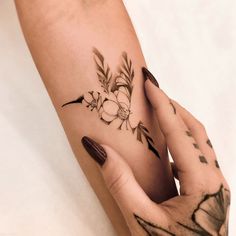 a woman's arm with flowers on it and her hand holding the wrist tattoo