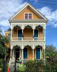 a yellow house with blue shutters and balconies on the second floor is decorated for halloween