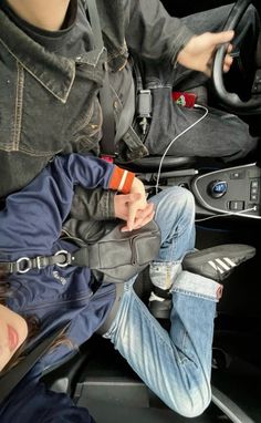 two people sitting in the back of a car, one holding a cell phone and listening to headphones