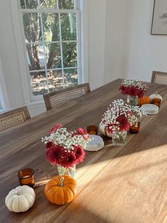 a wooden table topped with lots of vases filled with flowers and small pumpkins