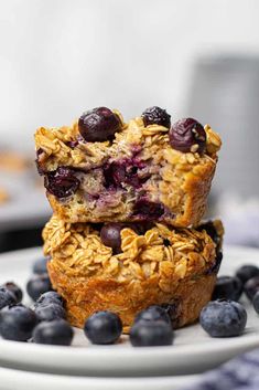 two blueberry muffins stacked on top of each other next to fresh blueberries