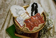 decorated cookies sitting on top of a table next to flowers and an old fashioned book