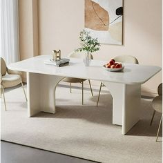 a white table with two chairs and a bowl of fruit on it in front of a painting