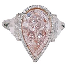 Absolutely stunning engagement ring style showcasing a Fancy Light Pink 3.25 carat pear-shaped diamond certified by GIA as VS2 clarity. The center stone surrounded by a round brilliant white diamonds halo, Flanked by two Cadillac cut diamonds total weight 1.29 ct. SI1 clarity, E color. Set in a polished 18K white gold. Total diamonds weight: 5.27 carat. This piece was handmade at the Novel Collection Jewelry Atelier, which specializes in rare collectible pieces in the Fancy color diamond. For ma Luxury Pink Teardrop Rings, Luxury Pink Gold Jewelry With Single Cut Diamonds, Luxury Pink Rings With Halo Setting, Luxury Pink Ring With Center Stone, Luxury Pink Rings With Single Cut Diamonds, Luxury Pink Rings With Diamond Accents, Luxury Pink Rings With Vs Clarity, Luxury Pink Halo Ring With Accent Stones, Luxury Pink Rose Cut Diamond Wedding Ring