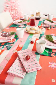 a table set for christmas dinner with plates, cups and napkins