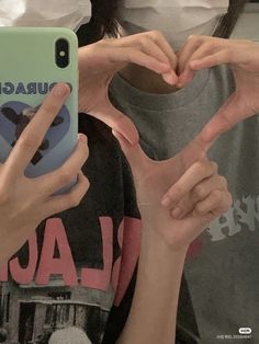 two people making the shape of a heart with their hands in front of an iphone