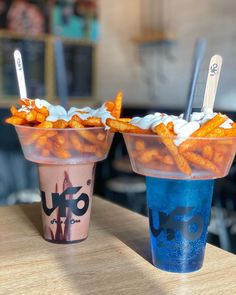 two plastic cups filled with food sitting on top of a wooden table next to each other