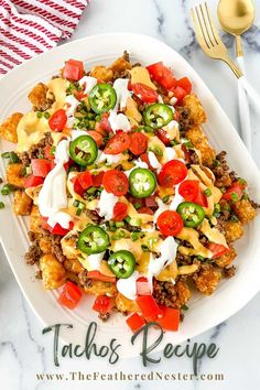 a white plate topped with nachos covered in cheese and toppings next to a fork