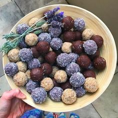 a person holding a bowl full of chocolate truffles with lavender sprigs on top