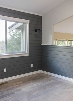 an empty room with wood flooring and gray paint on the walls, along with a window