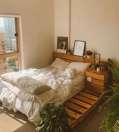 a bed made out of wooden pallets in a room with plants and pictures on the wall