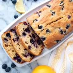 slices of blueberry lemon bread on a white platter next to sliced lemons