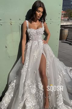 a woman in a white wedding dress leaning against a wall with her leg on the ground