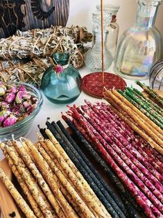 there are many different types of sticks on the table with flowers in glass vases