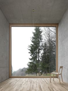 an empty room with a wooden floor and large window that looks out onto the forest