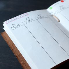 a close up of an open planner book on a wooden table with numbers and times