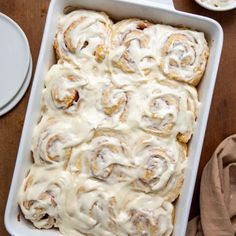 a pan filled with cinnamon rolls on top of a wooden table