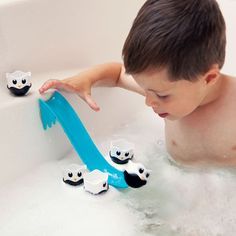 a young boy playing with toys in a bathtub filled with water and foams