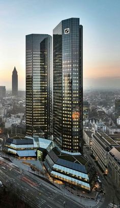 two tall skyscrapers are next to each other in the city at sunset or dawn