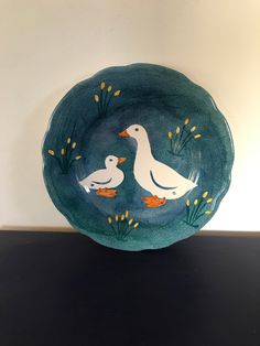 two white birds sitting on top of a green plate