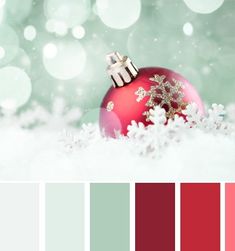 a red christmas ornament sitting on top of snow covered ground next to a green background