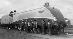 black and white photograph of men standing in front of an old train