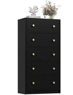 a black chest of drawers with gold handles and knobs on the bottom, next to a flower vase