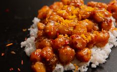 a close up of food on top of rice with sauce and orange zest sprinkles