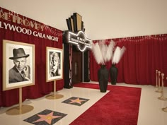 a red carpeted room with two black vases on the floor and pictures hanging up