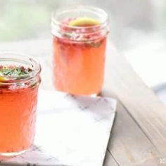 two mason jars filled with raspberry mint lemonade on top of a wooden table