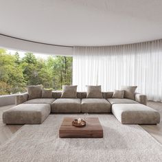 a living room with a large sectional couch in front of a white curtained window