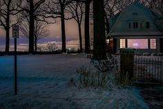 a house in the middle of winter with snow on the ground and trees around it