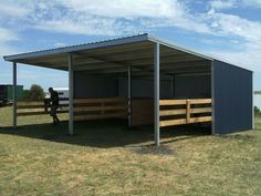 a person sitting on a bench in front of a metal structure with wood slats