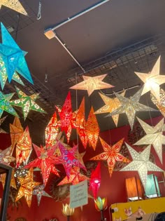 many colorful stars hanging from the ceiling in a room with red walls and yellow floors