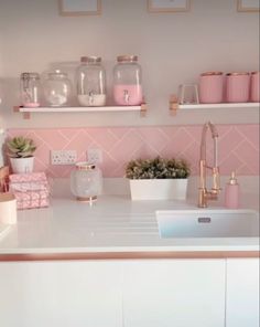 a kitchen with pink and white decor on the wall, shelves above the sink and below the faucet