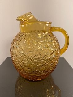 a yellow glass pitcher sitting on top of a white table