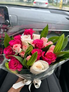 a bouquet of pink and white flowers sitting in the passenger seat of a car