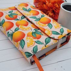 an orange print notebook with a cup of coffee next to it