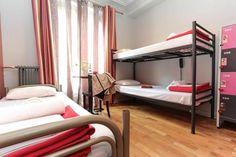 two bunk beds in a room with wooden floors and pink curtains on the windowsill