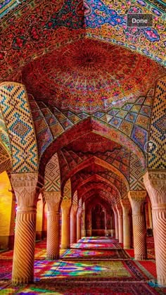 the inside of an ornate building with columns and colorful carpets on the floor, in bright colors