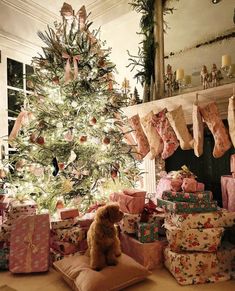 a dog sitting on a pillow in front of a christmas tree with presents under it