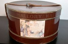 an old fashioned hat box on a black table with the name mallory hat printed on it