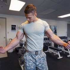 a man in the gym with his arms stretched out and one arm extended, looking down