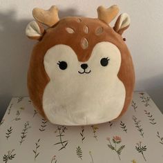 a brown and white stuffed animal with antlers on it's head sitting on top of a table